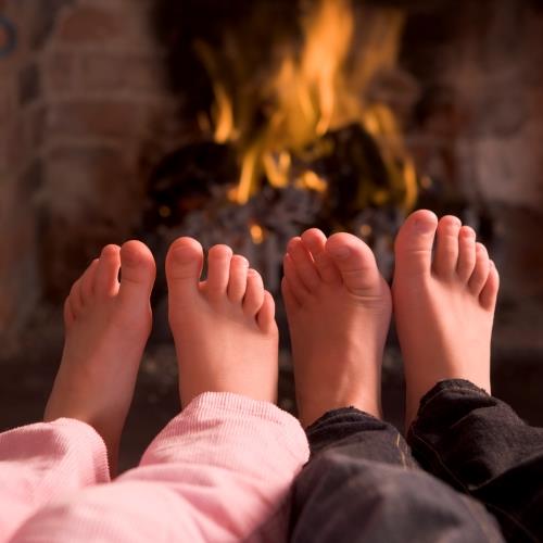 Children warming feet by fireplace
